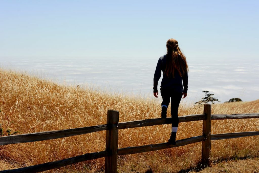 Woman climbing farm fence. Photo by Michael Rosner-Hyman on Unsplash

